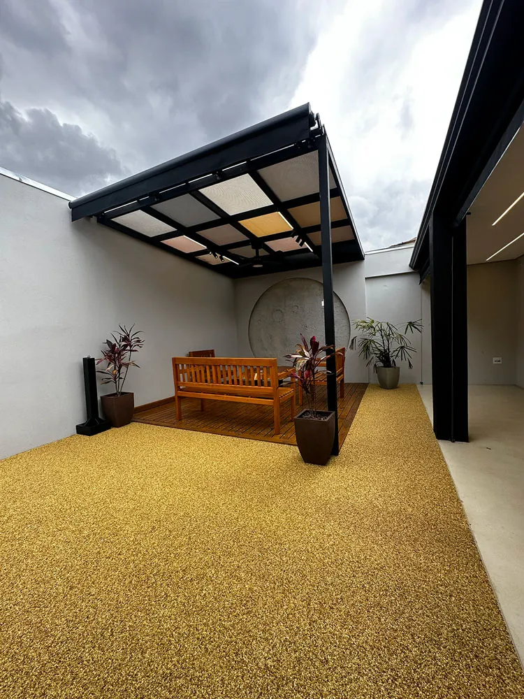Pátio externo com pergolado metálico e deck de madeira